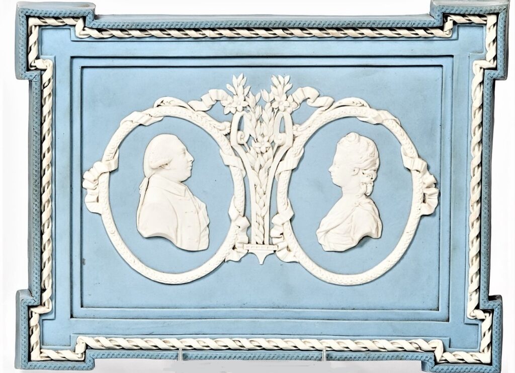 Light blue plaque with two white bas-relief silhouettes.