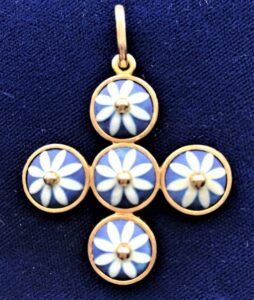 Pendant of five domed discs in cross arrangement, each ringed with gold and with white flower shape with golden center.