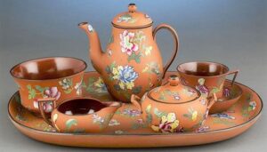 Terra-cotta-colored tea set with floral pattern.